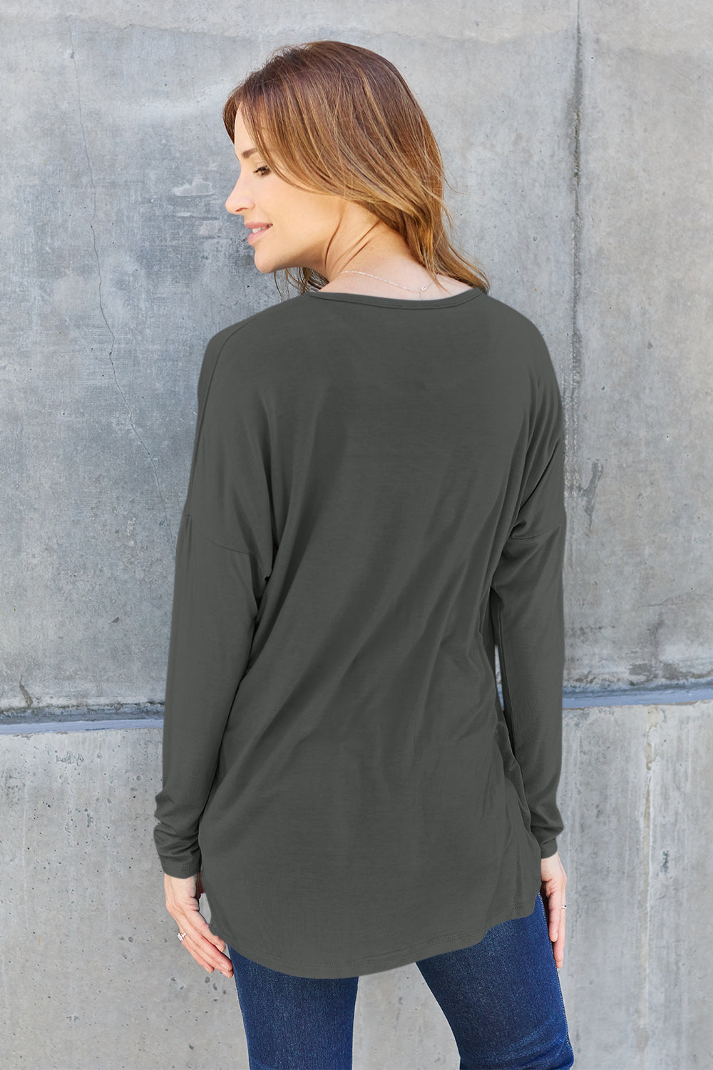 Woman wearing an olive green round neck dropped shoulder t-shirt with long sleeves, made from rayon and spandex blend.