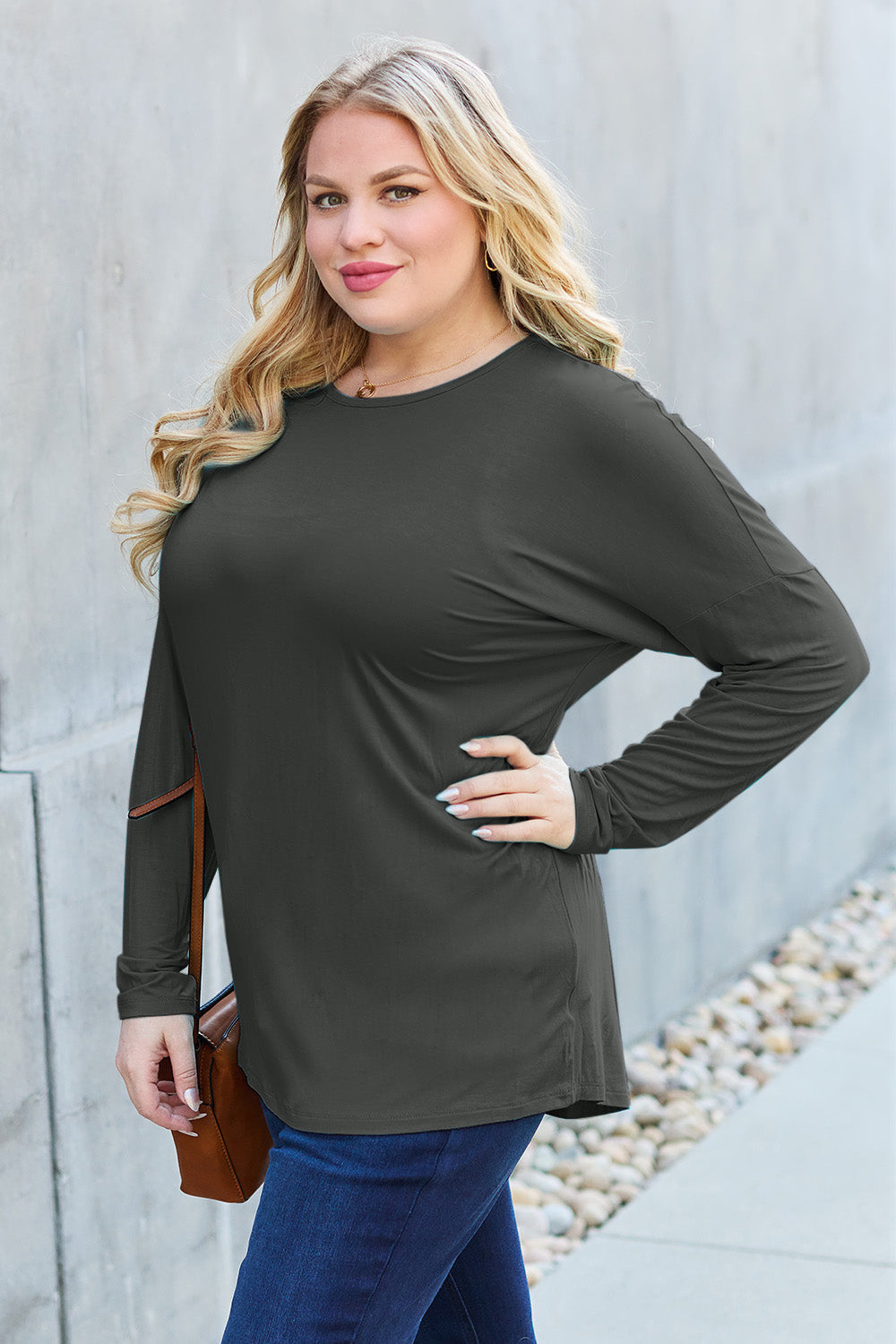 Woman wearing a round neck dropped shoulder T-shirt in opaque, slightly stretchy fabric with full size fit, in an outdoor setting.