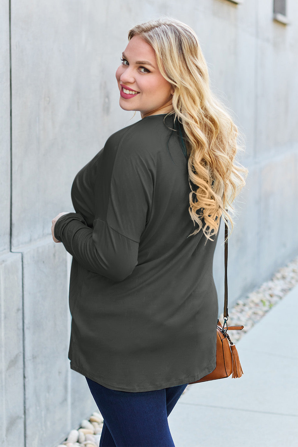 Woman wearing a round neck dropped shoulder T-shirt with a slight stretch, made from rayon and spandex, styled with a brown bag.