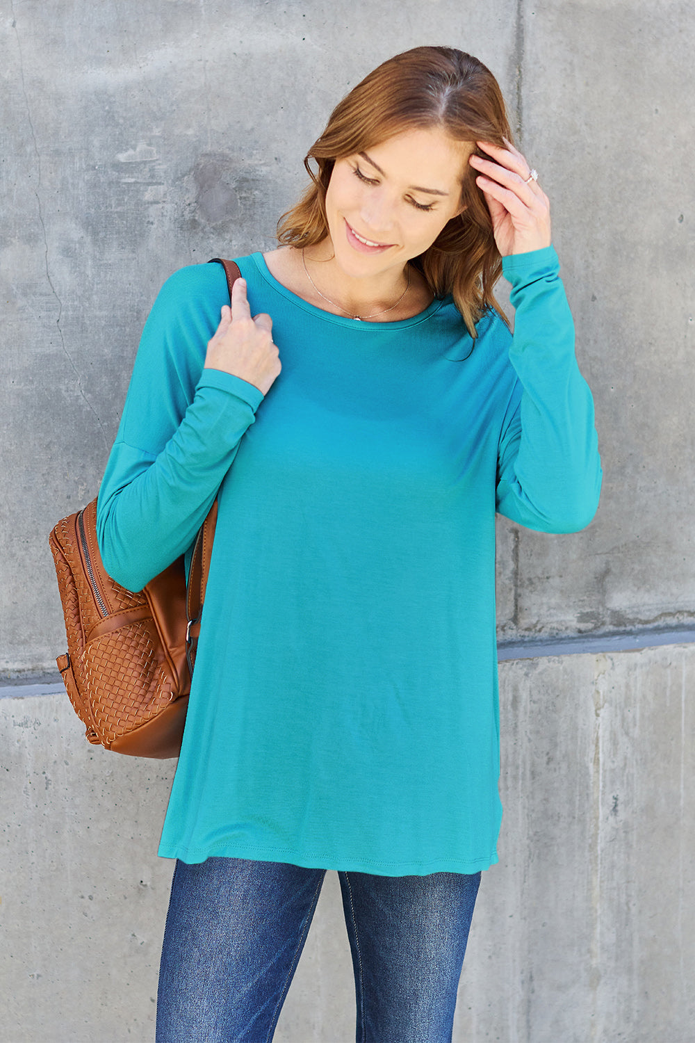 Woman wearing teal round neck dropped shoulder T-shirt paired with jeans, casual fashion style.