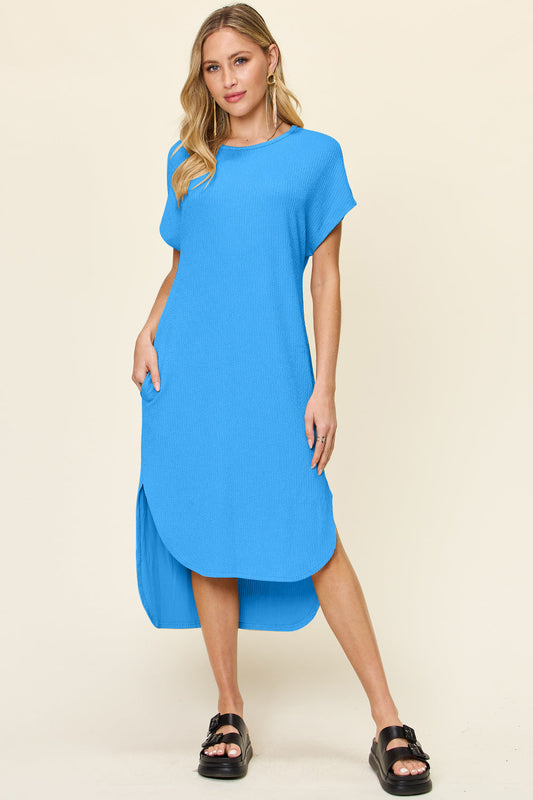 Woman wearing a blue round neck short sleeve slit dress with slight stretch, made from polyester and spandex.