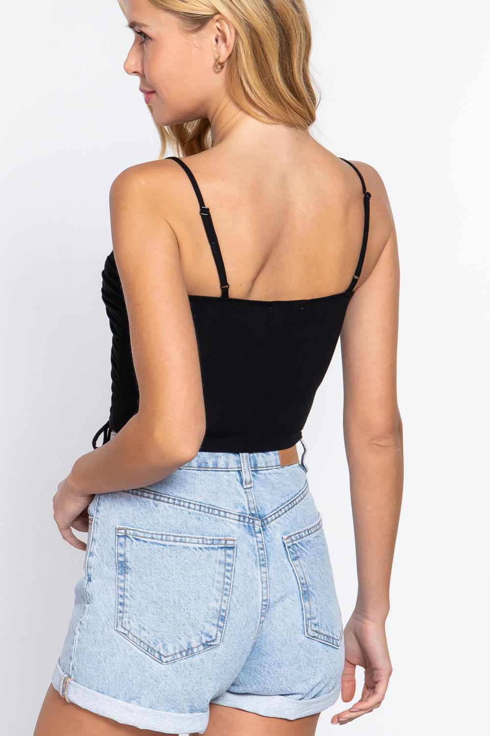 Woman wearing black ruched side shirring cami top with light denim shorts, showcasing back view of stylish summer outfit.