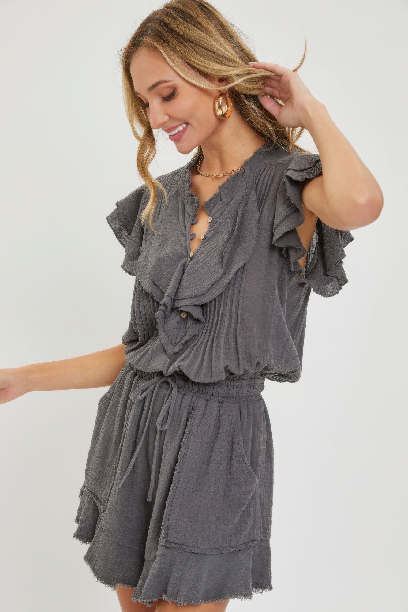 Woman wearing a grey ruffle romper with adjustable drawstring waist and smocked elastic waistband for a flattering fit