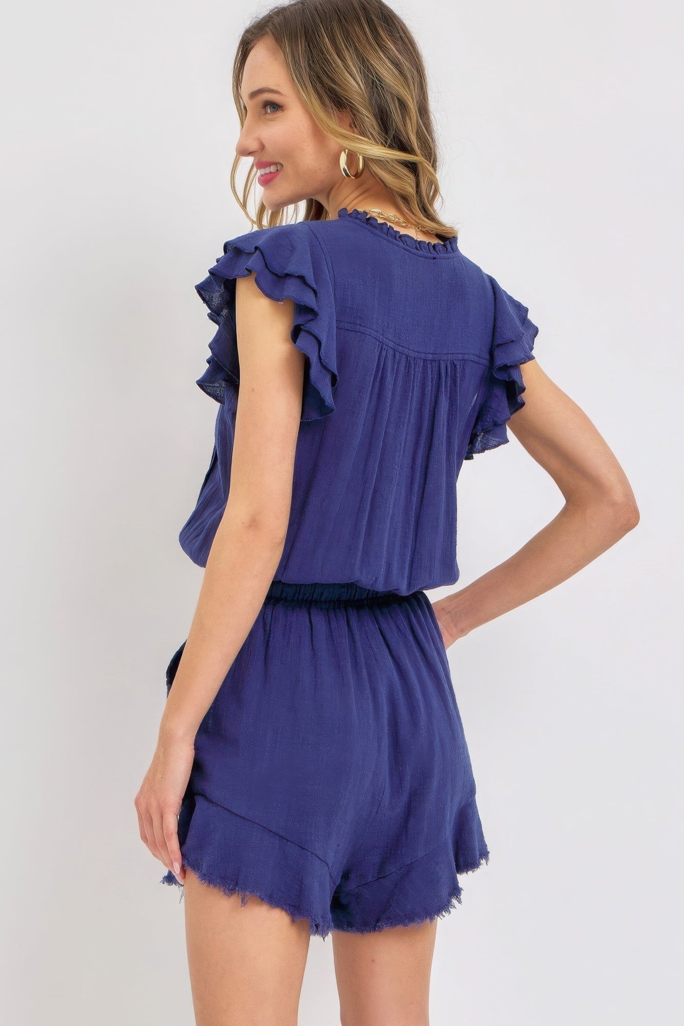 Woman wearing navy ruffle romper with elastic waistband and soft cotton fabric, perfect for spring and summer outings.