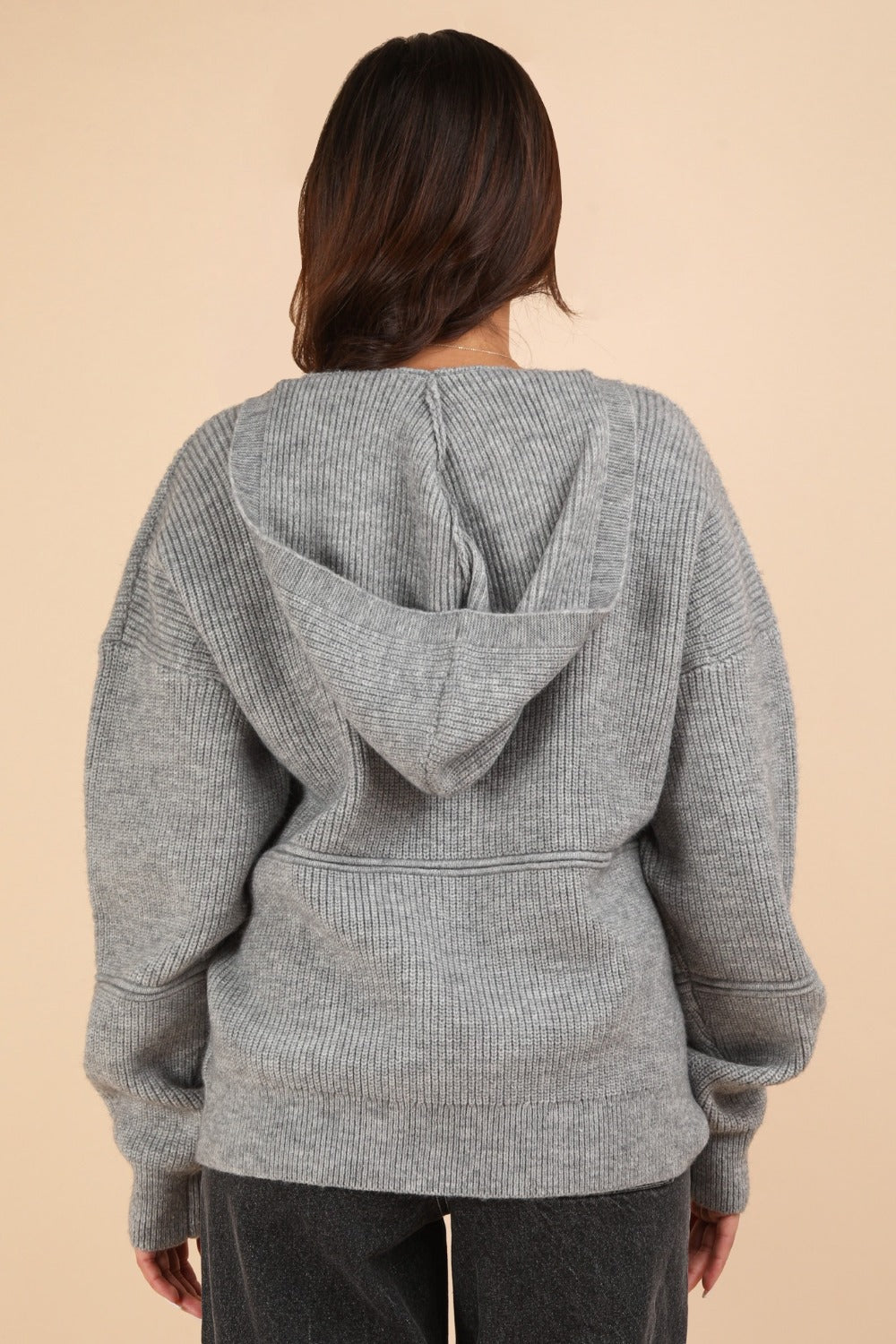 Gray seamless drop shoulder hooded sweater, ribbed detail, slightly stretchy fabric with 95% cotton, worn by a woman from the back.