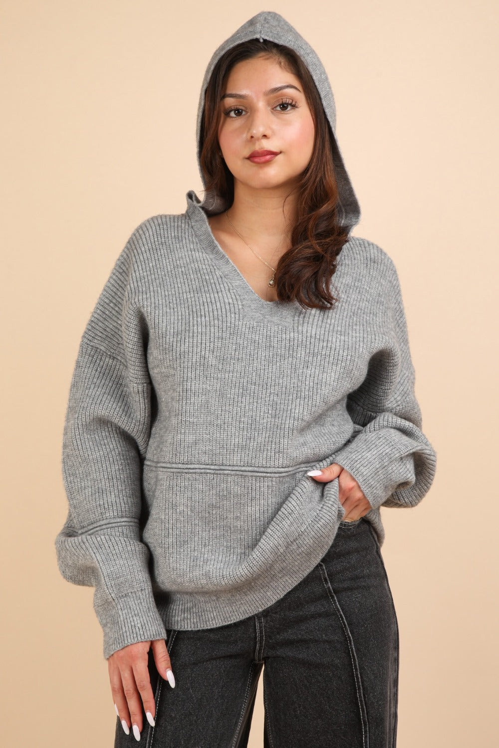 Woman wearing a gray ribbed drop shoulder hooded sweater with seam detail, made of 95% cotton and 5% spandex, slightly stretchy material.