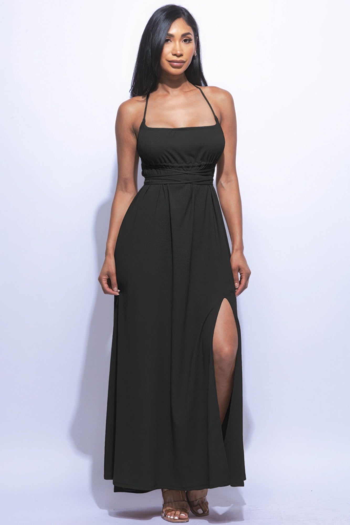 Woman wearing black side slit maxi skirt with strappy tie back, showcasing elegant design and flattering flare silhouette.