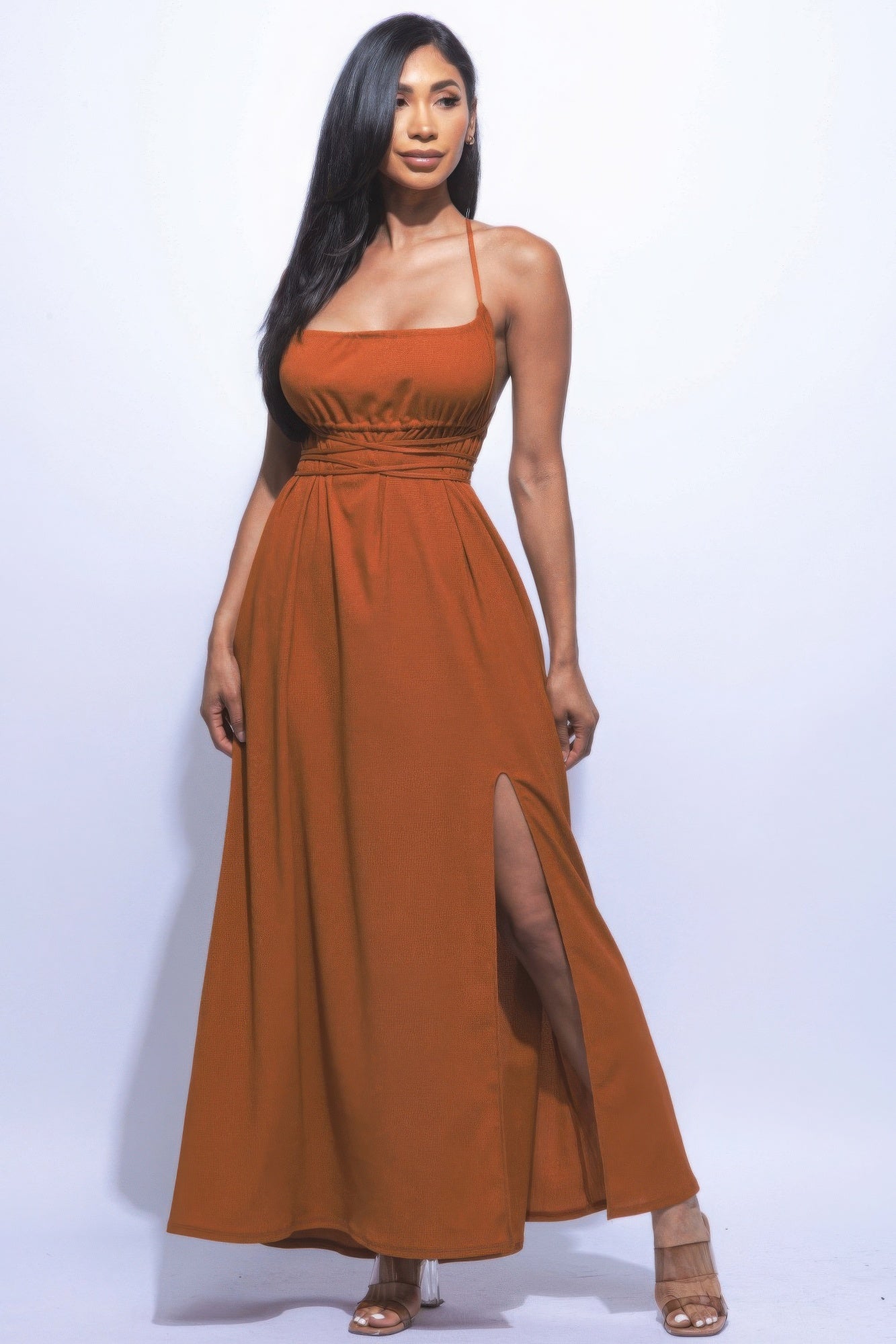 Elegant woman in an orange maxi dress with side slit and strappy tie back, showcasing a sophisticated, chic style.