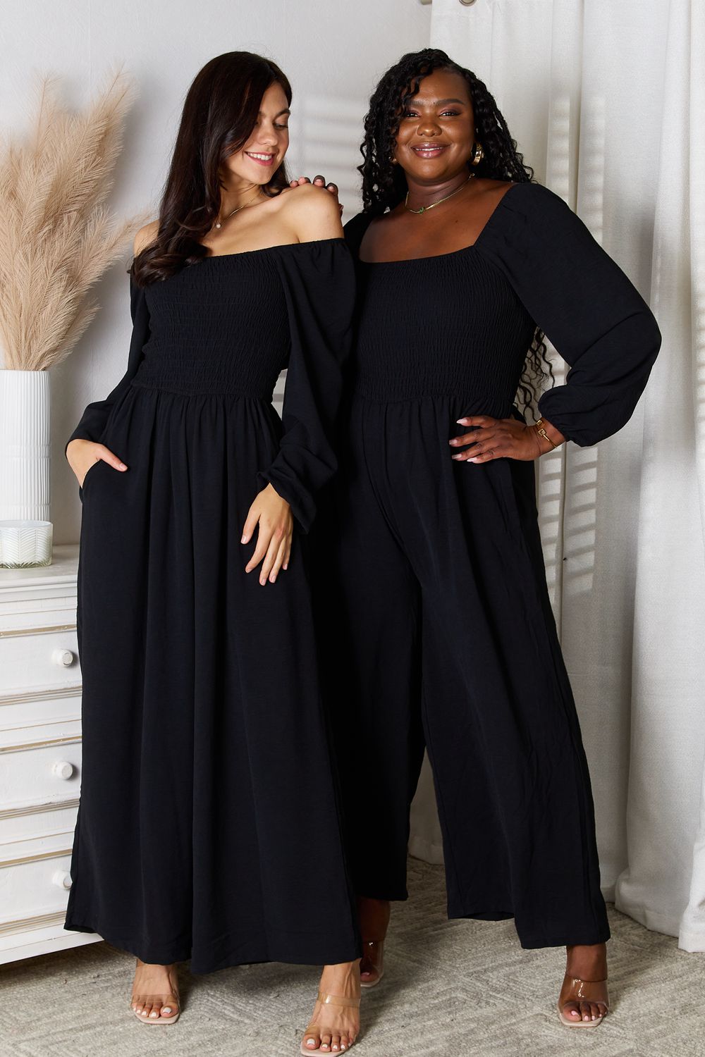 Two models wearing black Double Take Square Neck Jumpsuits with Pockets, showcasing versatile and stylish fits for diverse body types.