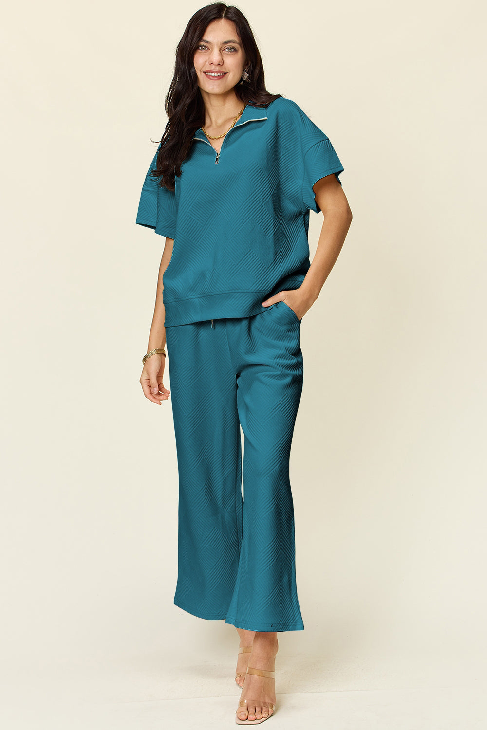 Turquoise two-piece set with half zip top and wide-leg pants. Features pockets and drawstring. Made of slightly stretchy polyester blend.