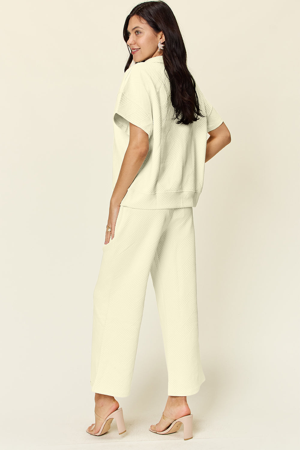 Woman wearing a texture half zip short sleeve top and pants set with pockets and drawstring, made of slightly stretchy polyester-spandex blend.