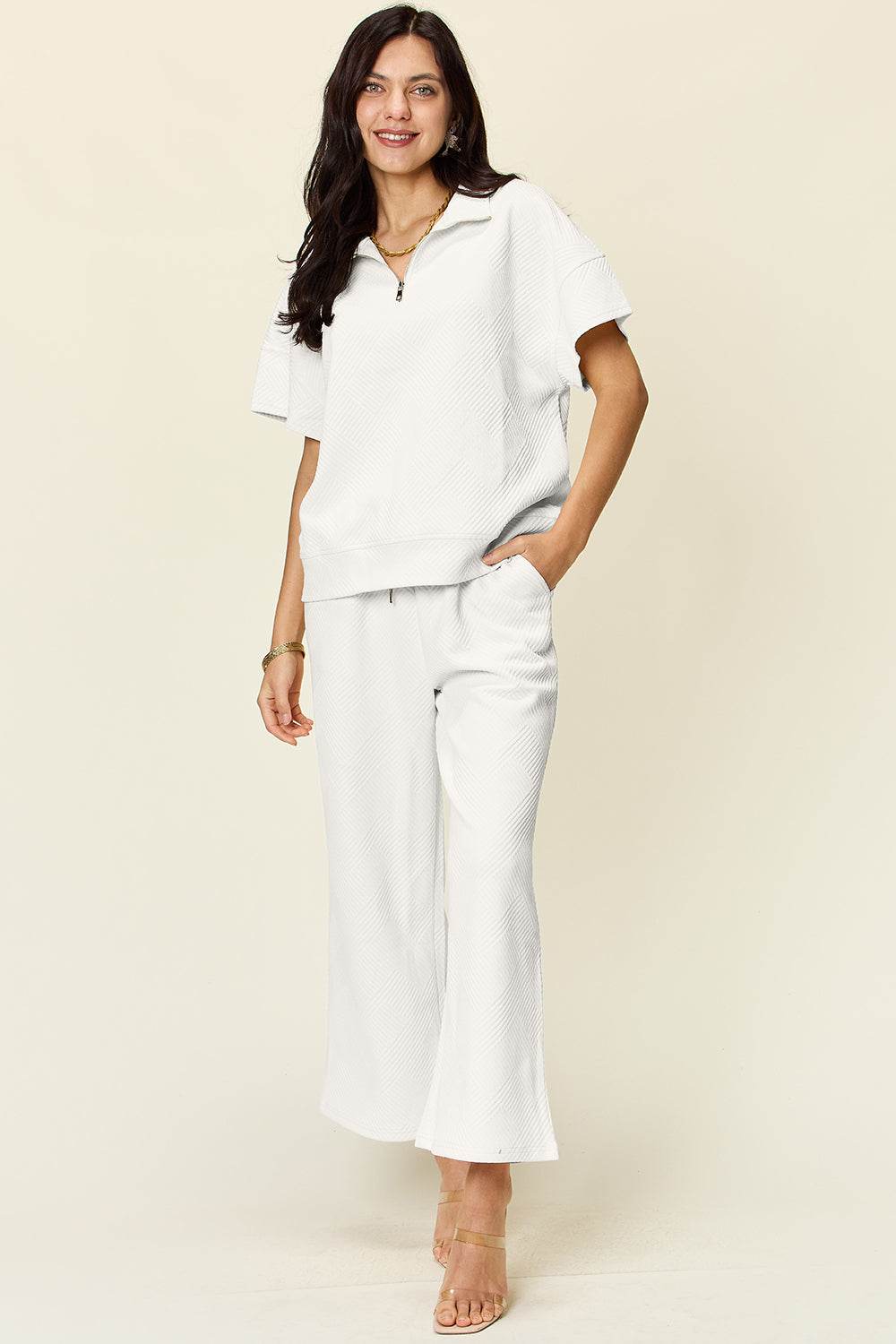 Woman wearing white texture half zip short sleeve top and pants set, pocketed and drawstring, slightly stretchy polyester-spandex fabric.