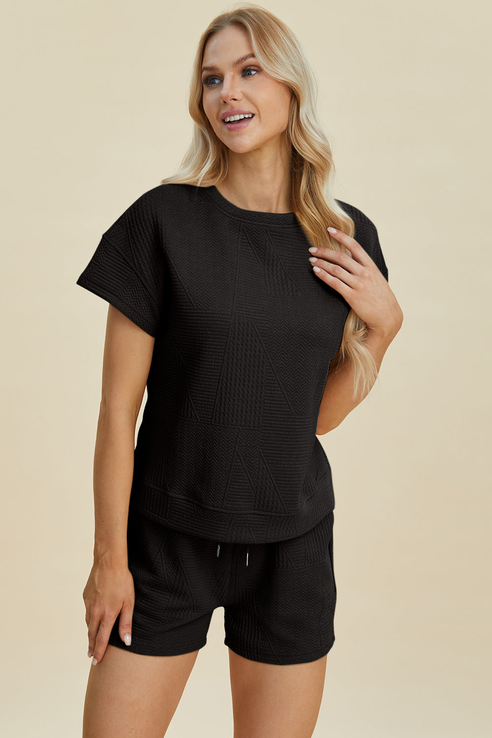 Woman wearing full size texture short sleeve top and shorts set with pockets and drawstring, made of polyester and elastane.