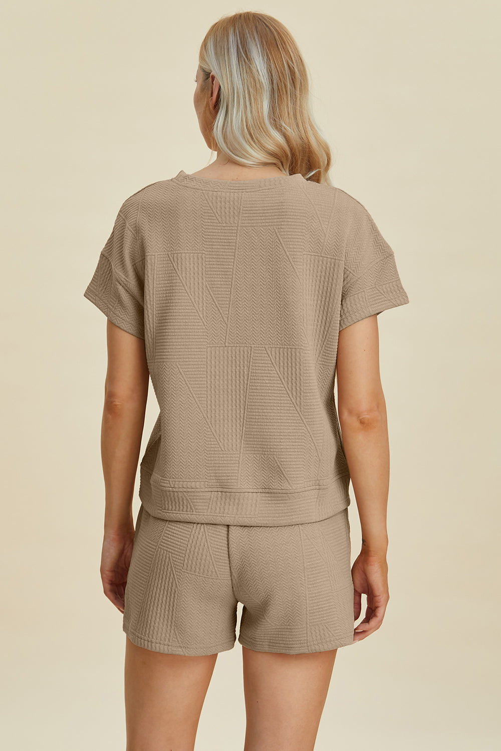 Woman wearing a full size textured short sleeve top and shorts set, featuring pockets and drawstring, made from polyester and elastane.