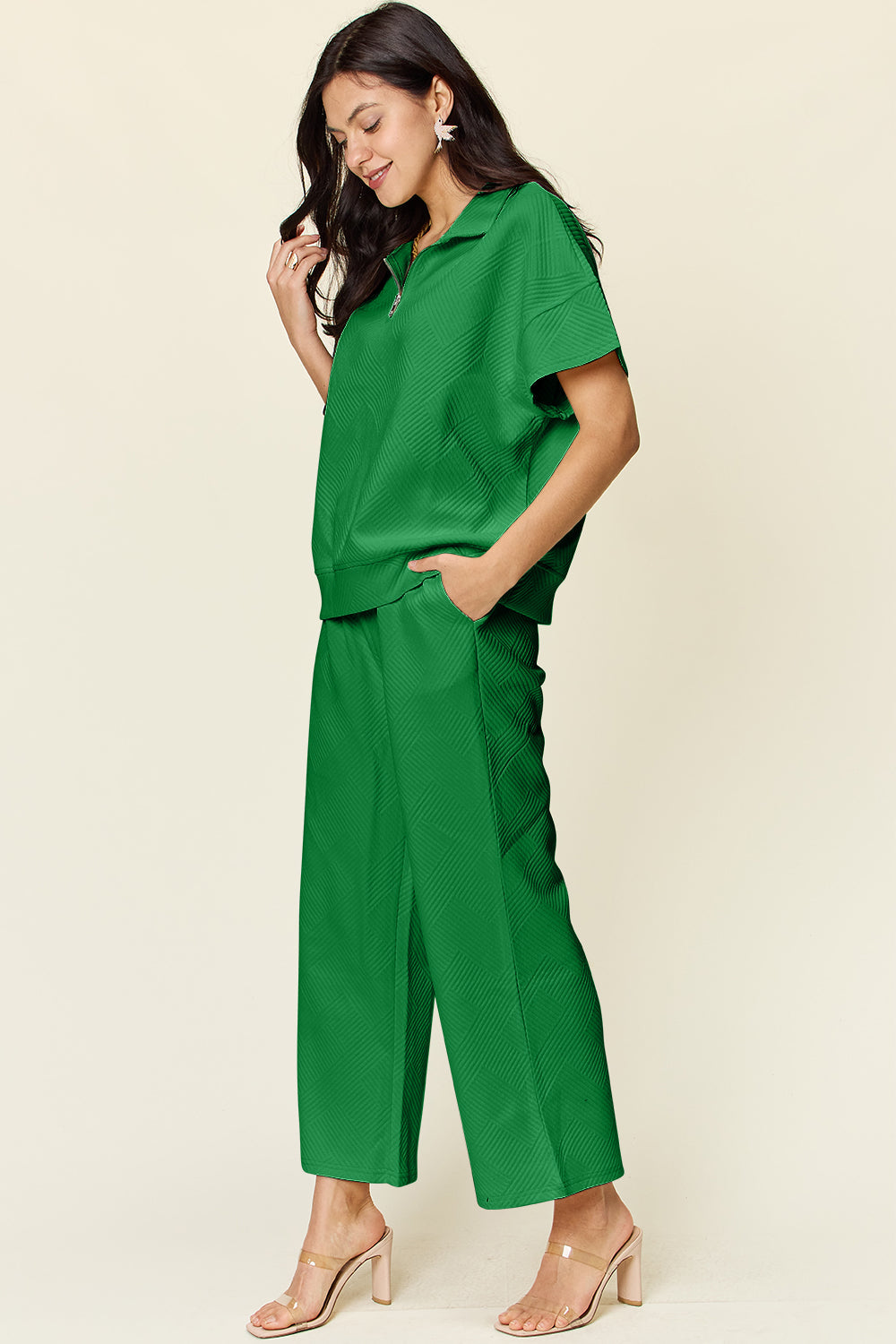 Woman wearing a green full-size texture half zip short sleeve top and pants set with pockets and drawstring, 97% polyester, 3% spandex.