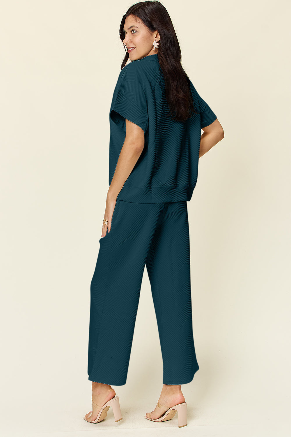 Woman wearing full size teal half zip short sleeve top and pants set with pockets, featuring slightly stretchy polyester blend.