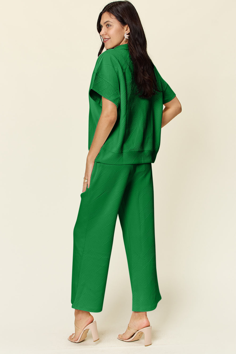 Woman wearing green two-piece set with half zip top and pants, featuring pockets and drawstring, slightly stretchy polyester-spandex blend.