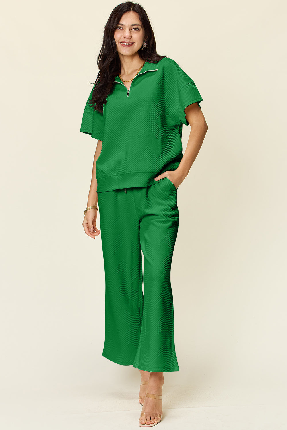 Woman wearing green full-size texture half zip short sleeve top and pants set with pockets and drawstring, slightly stretchy fabric.