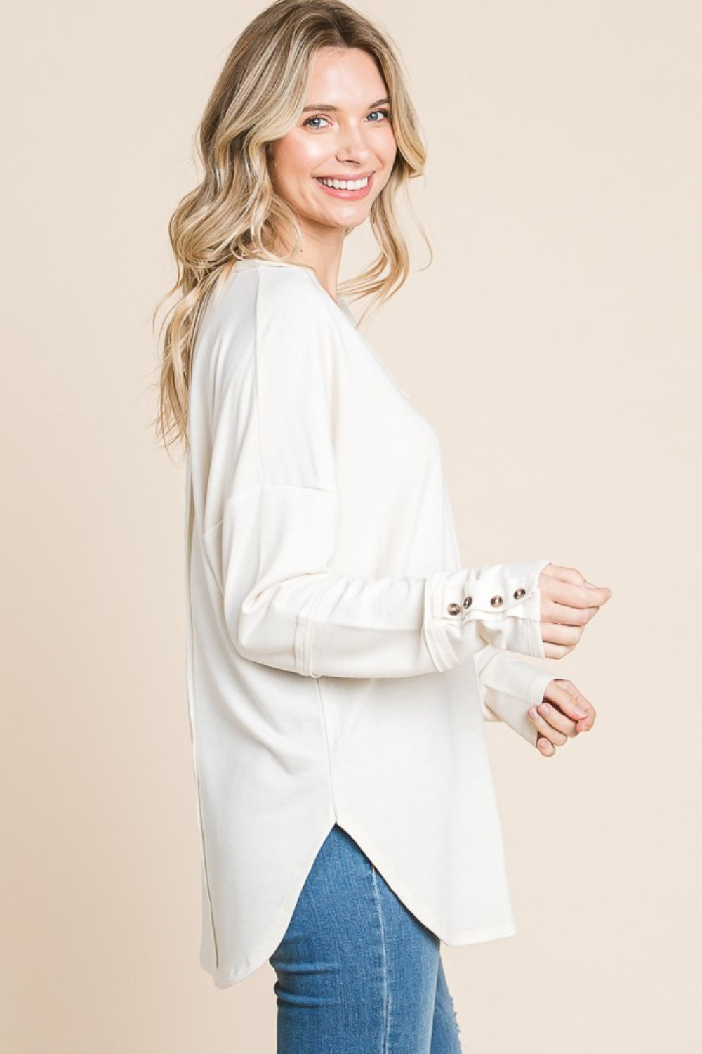 Woman wearing a white V-Neck Dropped Shoulder Blouse with long sleeves, showcasing the side and cuff details.