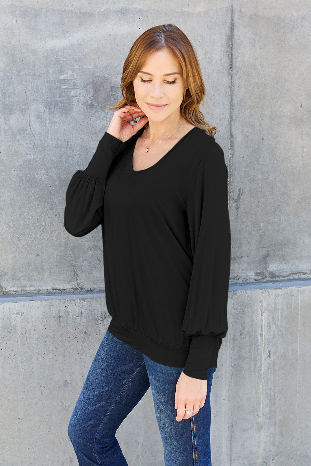 Woman wearing black V-Neck Lantern Sleeve Top with jeans, showcasing basic style and slight stretch fabric in rayon and spandex.