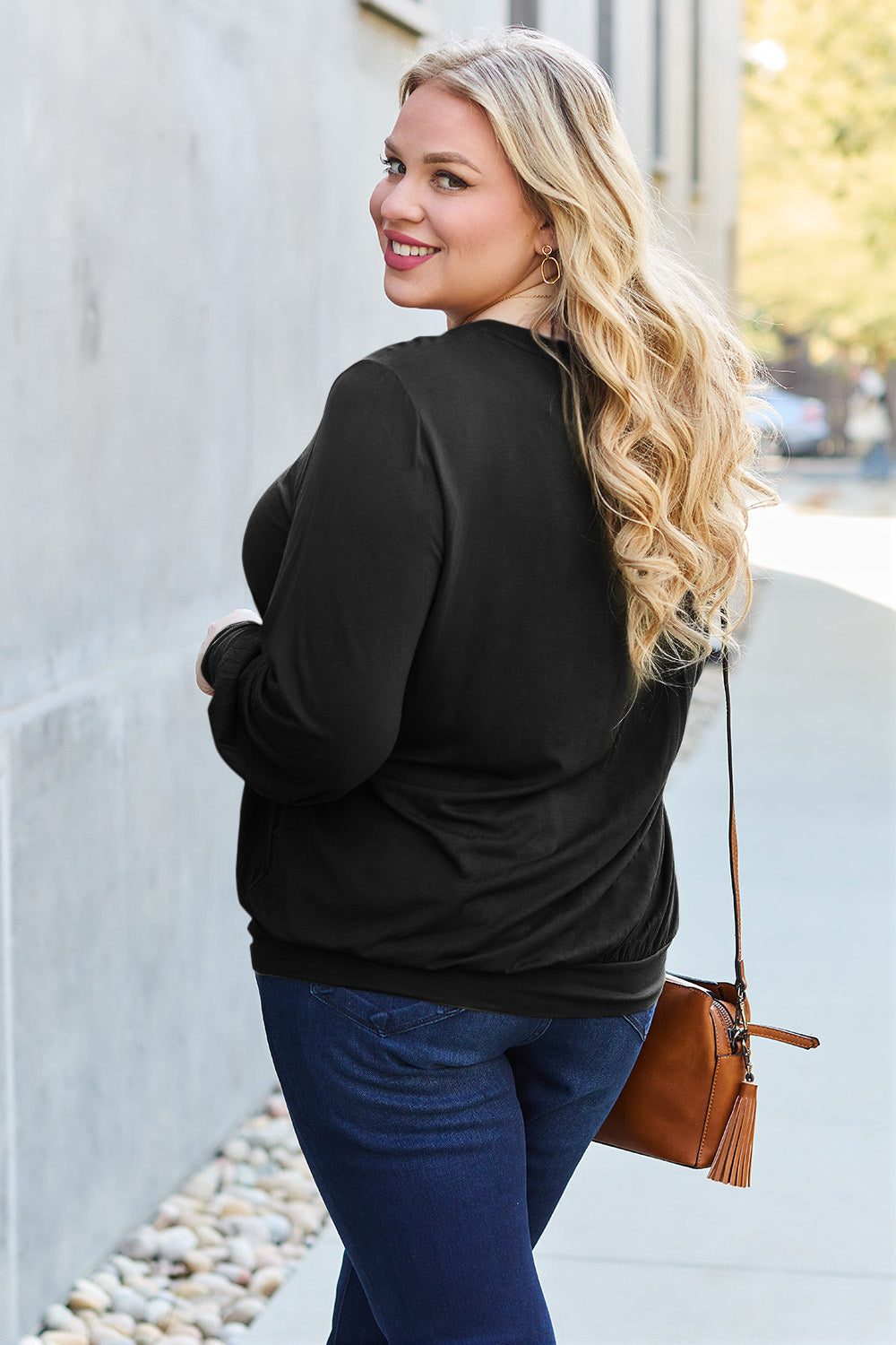 Woman wearing black V-Neck Lantern Sleeve Top with jeans, casually posing outdoors.