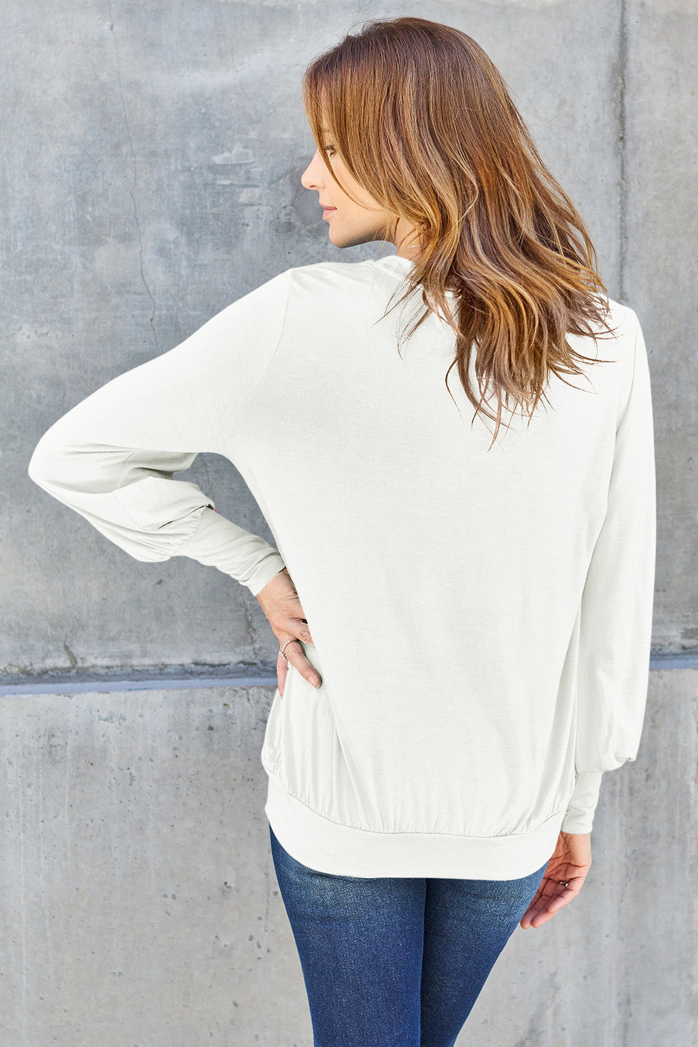 Woman wearing a white V-neck lantern sleeve top with a slightly stretchy fit, made of 95% rayon and 5% spandex, seen from the back.