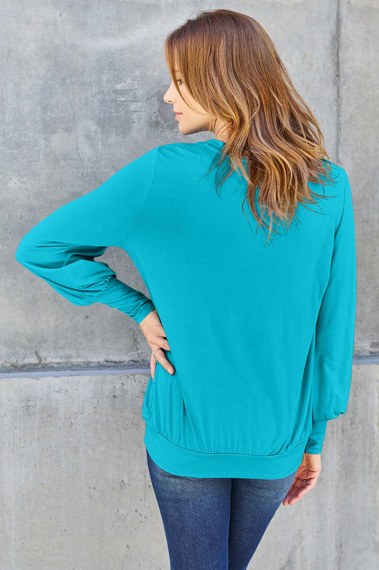 Woman wearing a teal V-neck lantern sleeve top with a slightly stretchy fit, made from 95% rayon and 5% spandex.