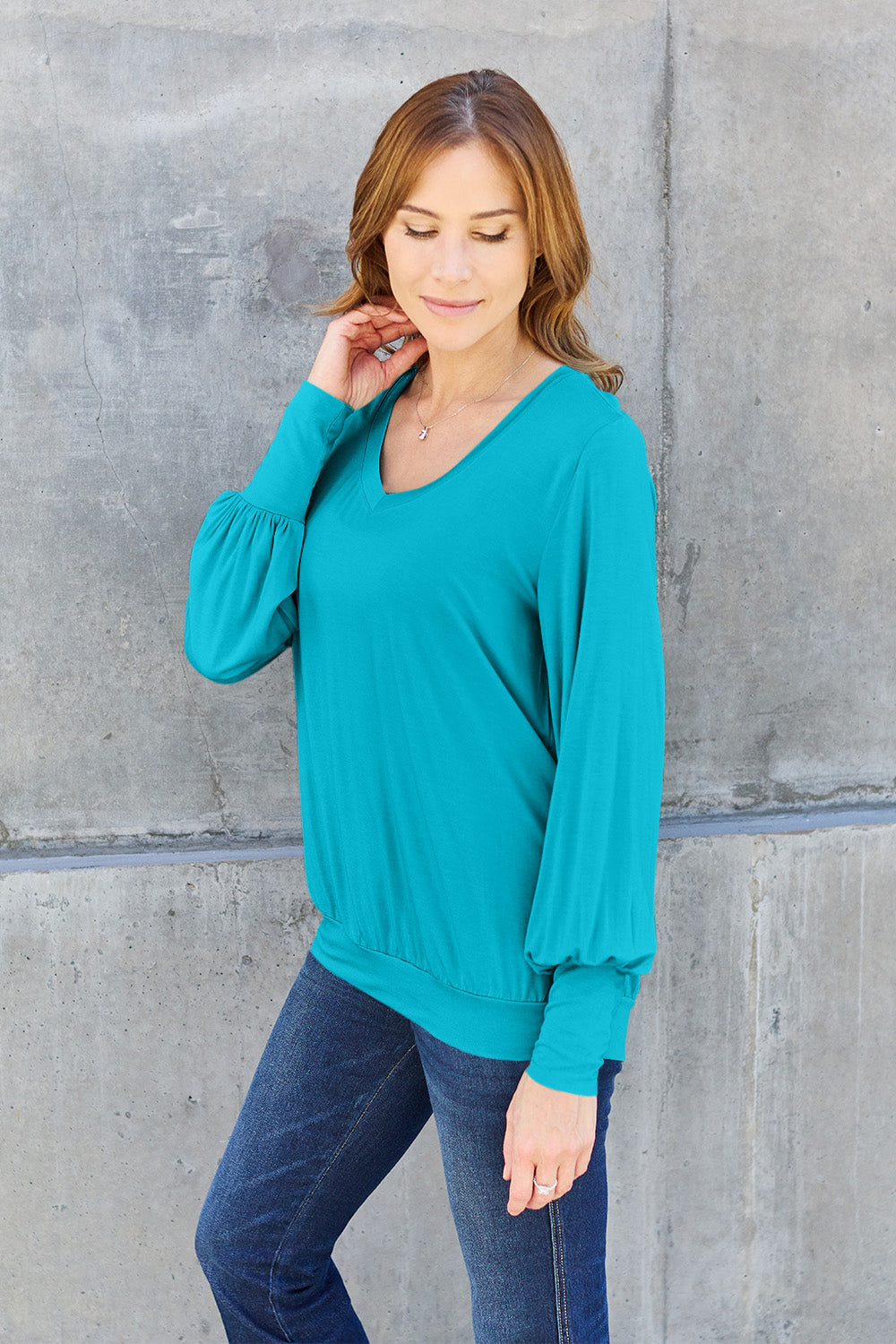 Woman wearing teal V-neck lantern sleeve top with slightly stretchy fabric, perfect for everyday style.