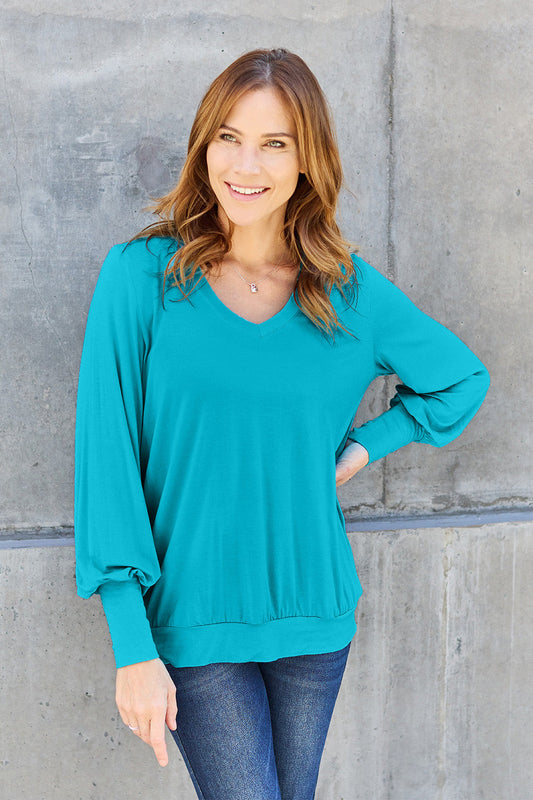 Woman wearing a teal V-Neck Lantern Sleeve Top made of 95% rayon and 5% spandex, featuring a basic style and slightly stretchy fabric.