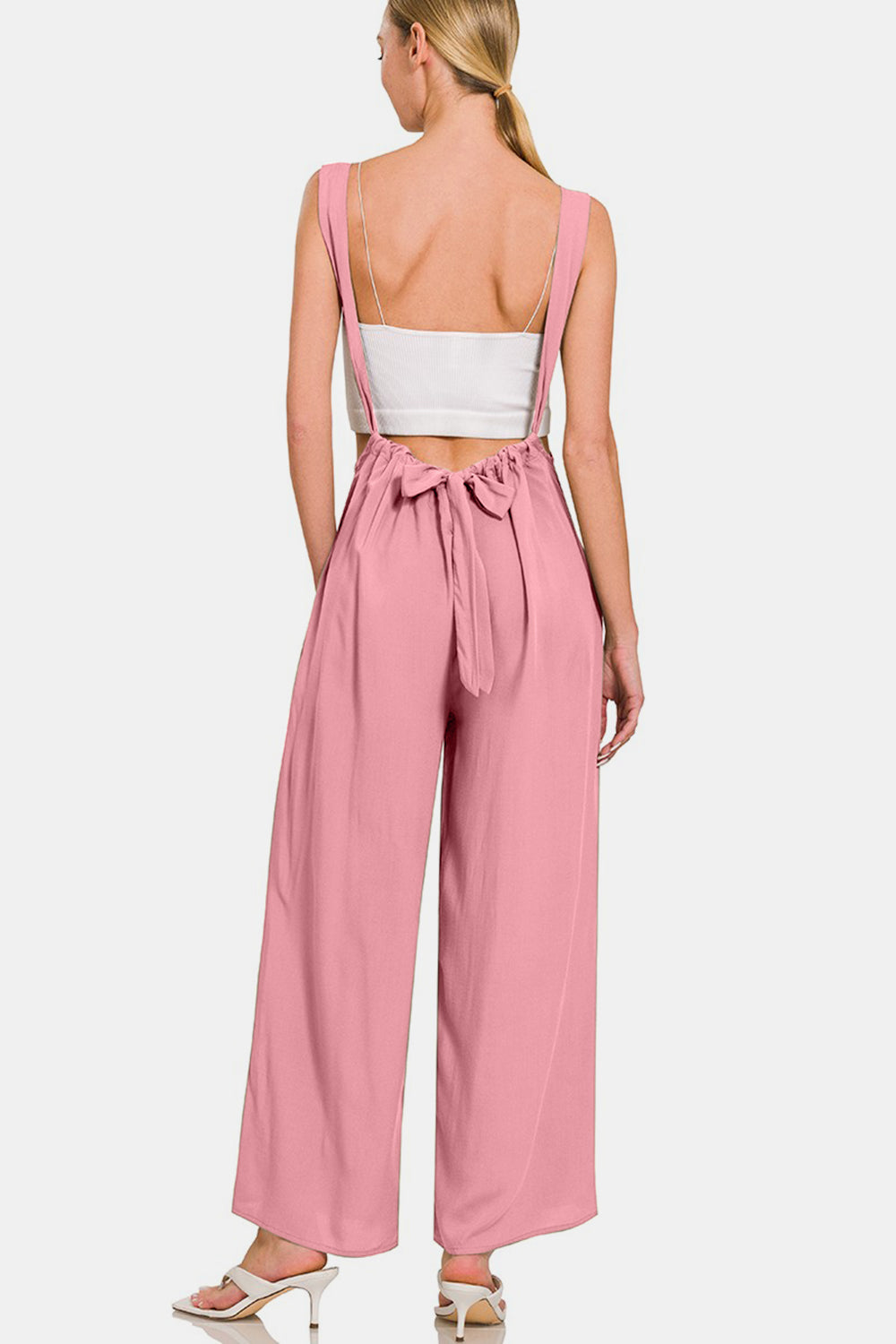 Stylish pink wide-leg overalls with wide straps and back tie detail, perfect for trendy and versatile styling.