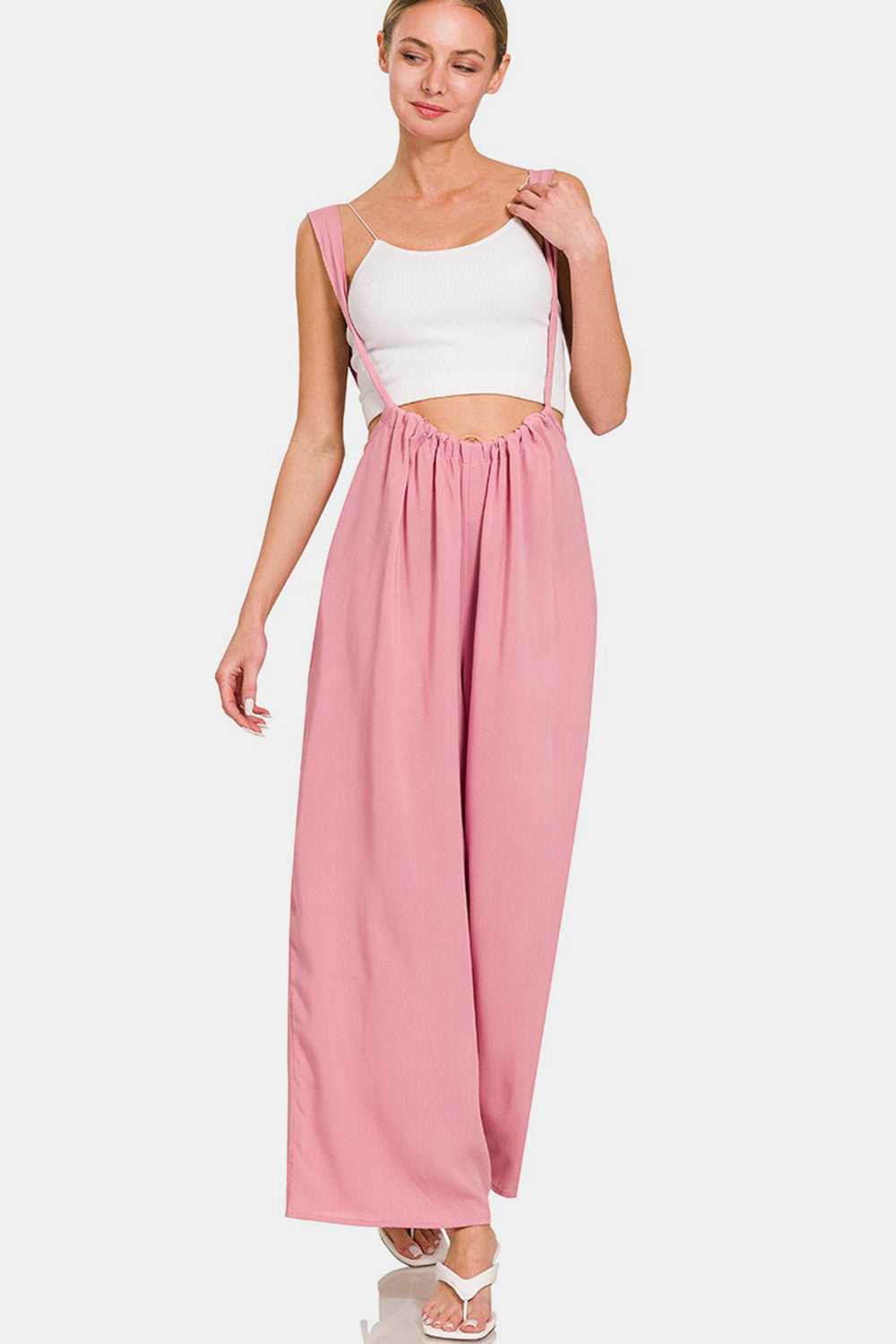 Trendy pink wide-leg overalls with sheer ruched bodice and wide straps, featuring convenient pockets and comfortable rayon fabric.