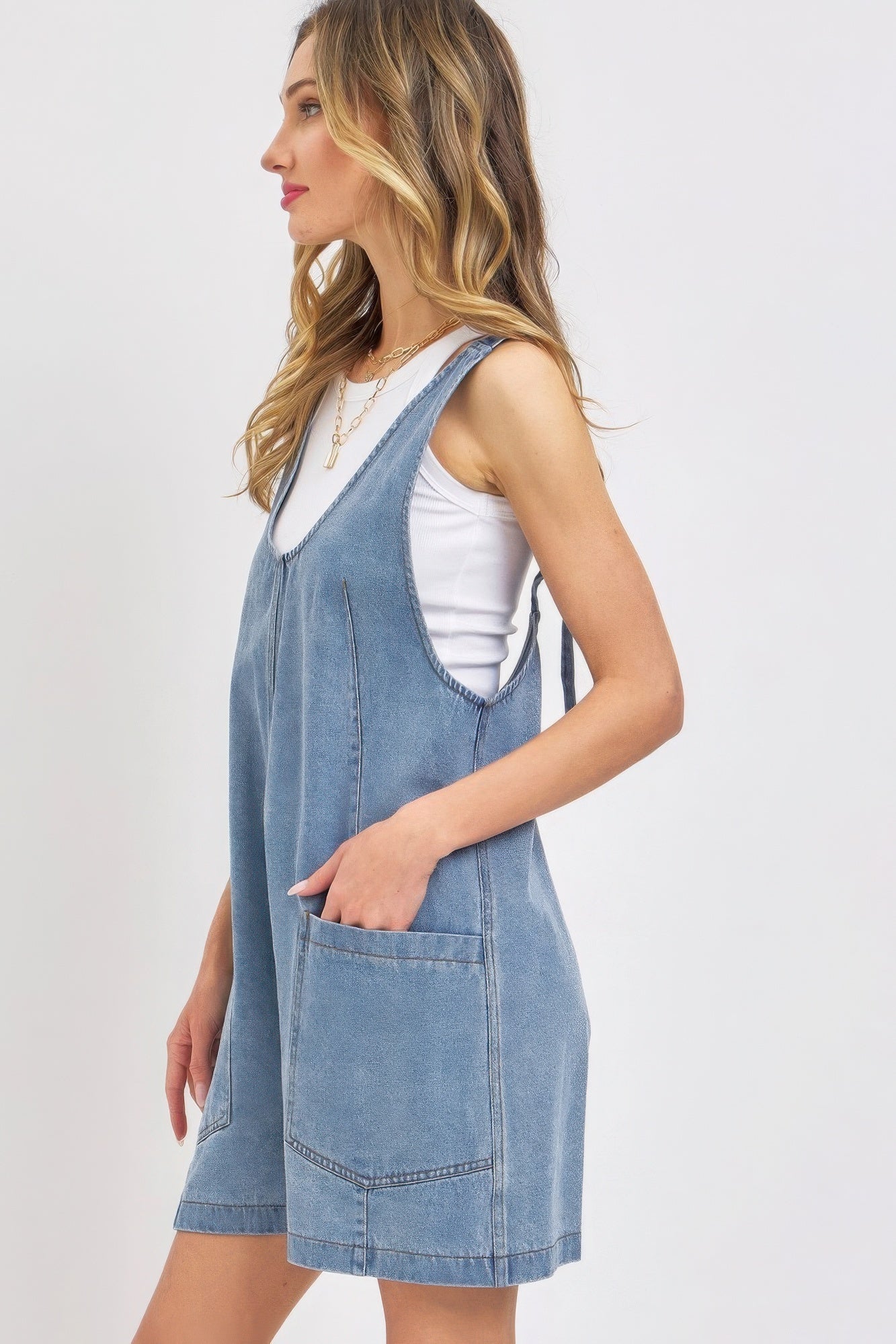 Woman wearing a summer denim overall romper with oversized patch pockets and adjustable straps, perfect for casual outings.