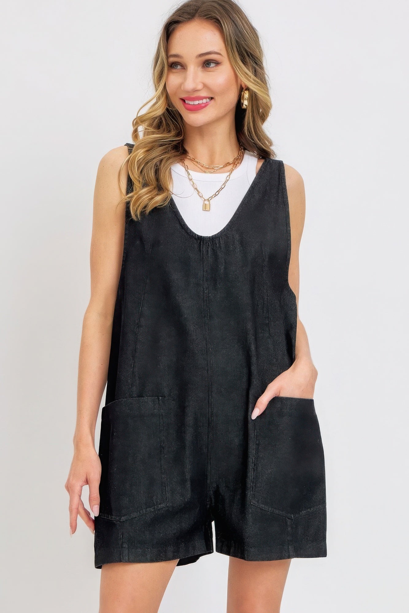 Woman wearing black summer denim overall romper with oversized pockets and adjustable straps.