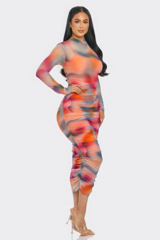Woman wearing Summer Heat Print Mesh Ruched Midi Dress in vibrant Tomato/Purple print with long sleeves and smock neck.