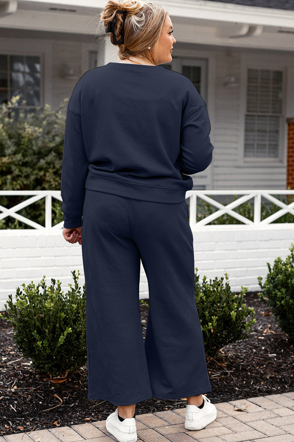 Woman wearing a navy textured long sleeve top and drawstring pants set, standing outdoors, showcasing comfortable and stylish loungewear.