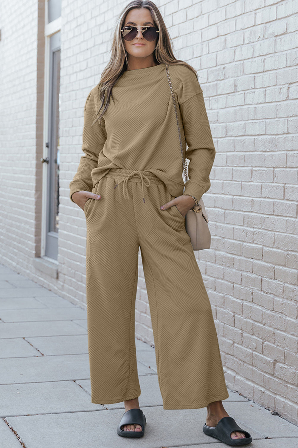 Woman wearing a textured long sleeve top and drawstring pants set in beige, stylish street fashion with slight stretch fabric.