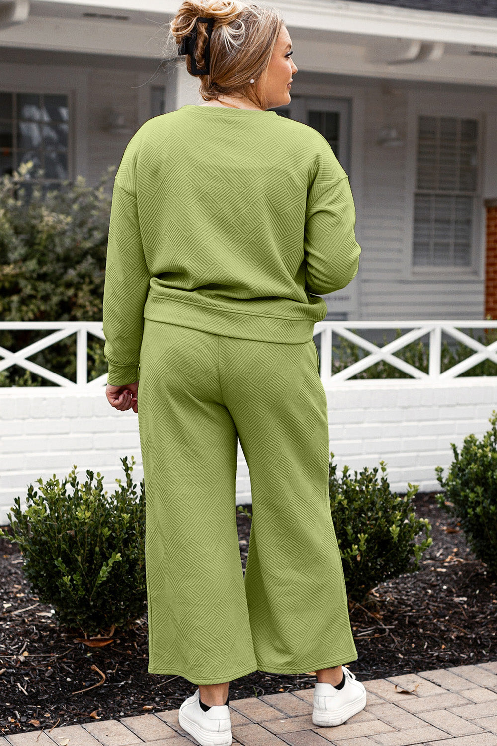 Woman wearing textured green long sleeve top and drawstring pants set outside a house, casual stylish outfit ensemble.