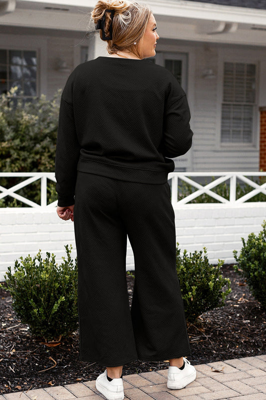 Woman wearing black textured long sleeve top and drawstring pants set, standing outdoors near a white fence.