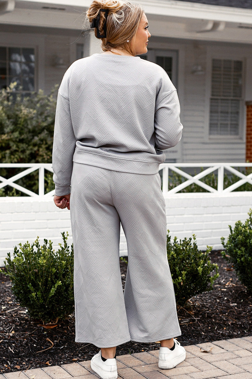 Woman in a textured long sleeve top and drawstring pants set, slightly stretchy fabric, outdoor background, showcasing casual style.