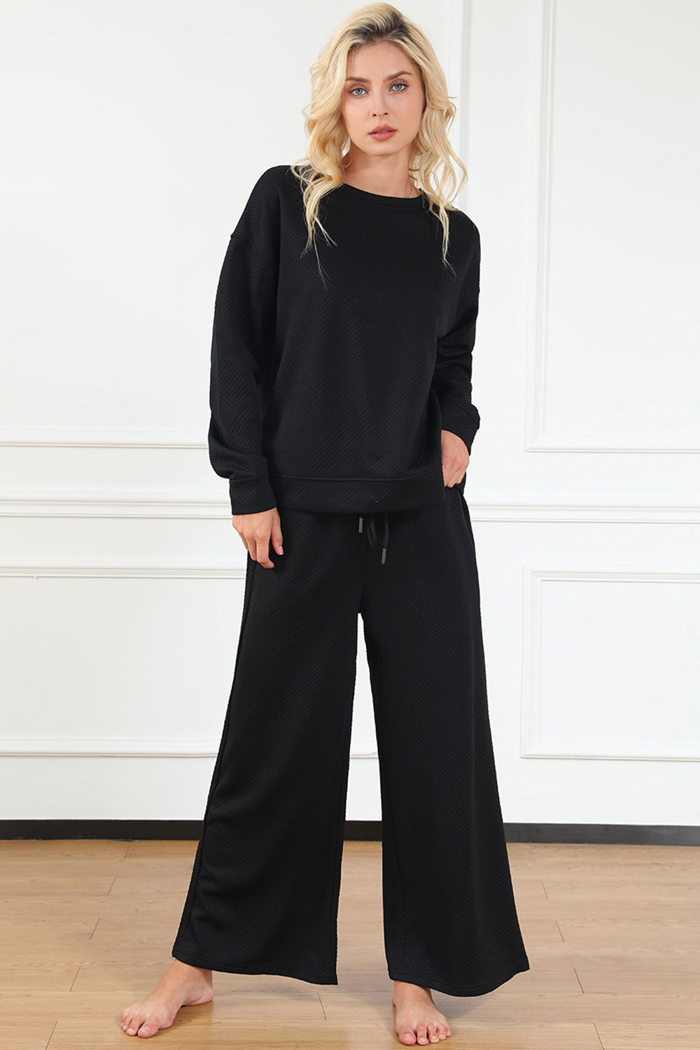 Woman wearing a textured long sleeve top and drawstring pants set in black, featuring a slightly stretchy fabric.