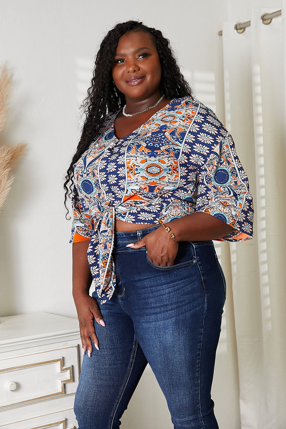 Woman wearing a patterned Tie Hem V-Neck Three-Quarter Sleeve Blouse with denim jeans, showcasing chic casual style.