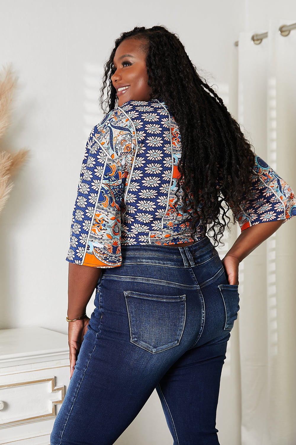 Woman wearing colorful three-quarter sleeve blouse with jeans, showcasing back view in a stylish and casual setting.