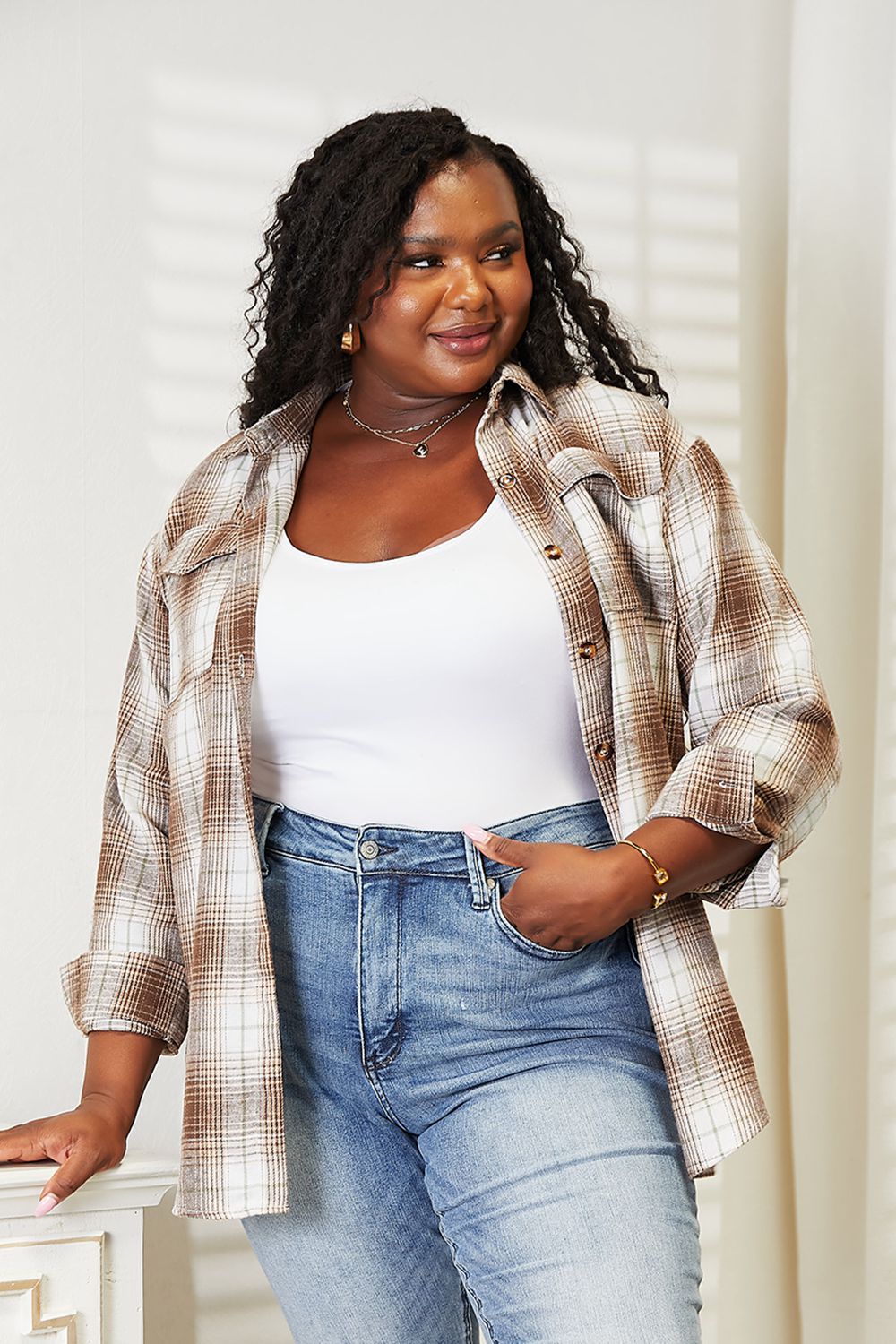 Woman wearing plaid dropped shoulder shirt with white top and jeans, showcasing effortless elegance and versatile styling.