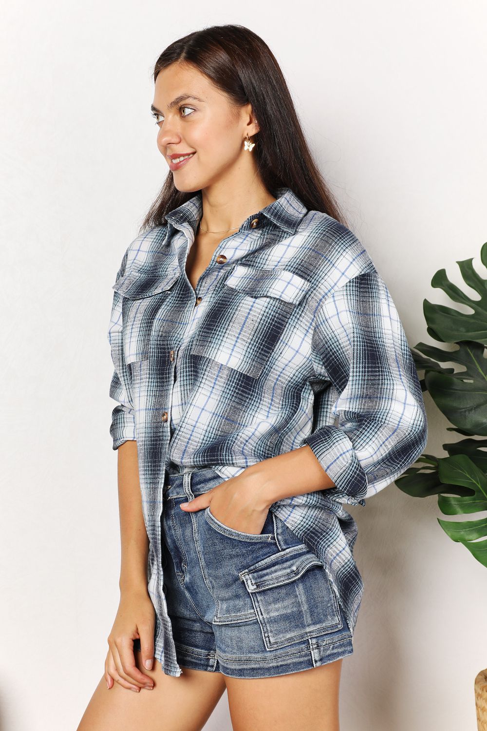 Woman wearing plaid dropped shoulder shirt with denim shorts, showcasing effortless elegance and versatile styling