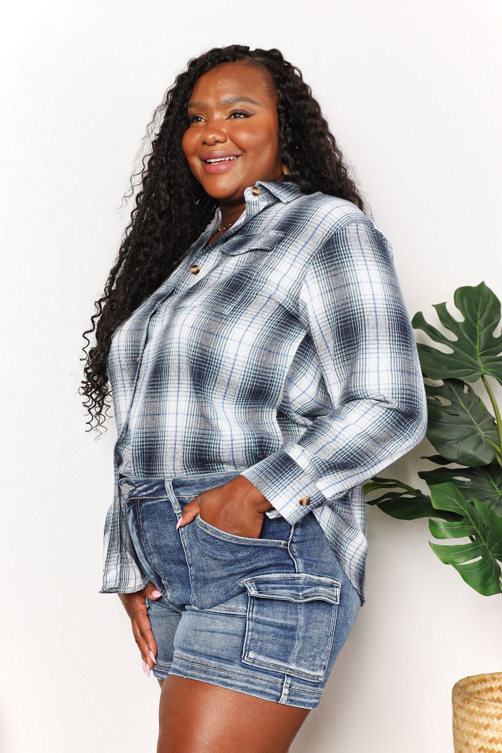 Woman wearing plaid dropped shoulder shirt in blue with denim shorts, showcasing effortless elegance and versatile style.