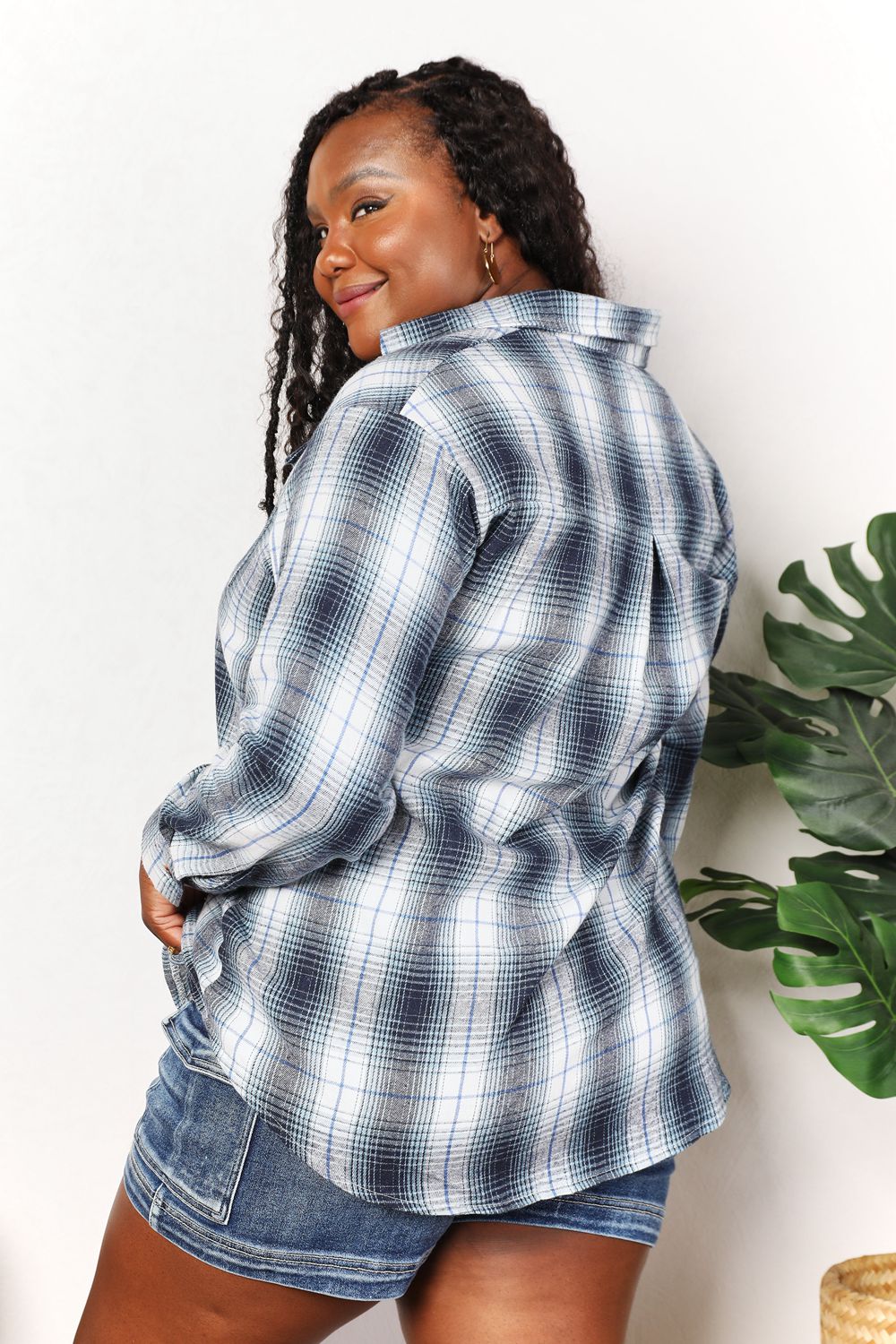 Woman wearing plaid dropped shoulder shirt with denim shorts, highlighting timeless style and versatile elegance.