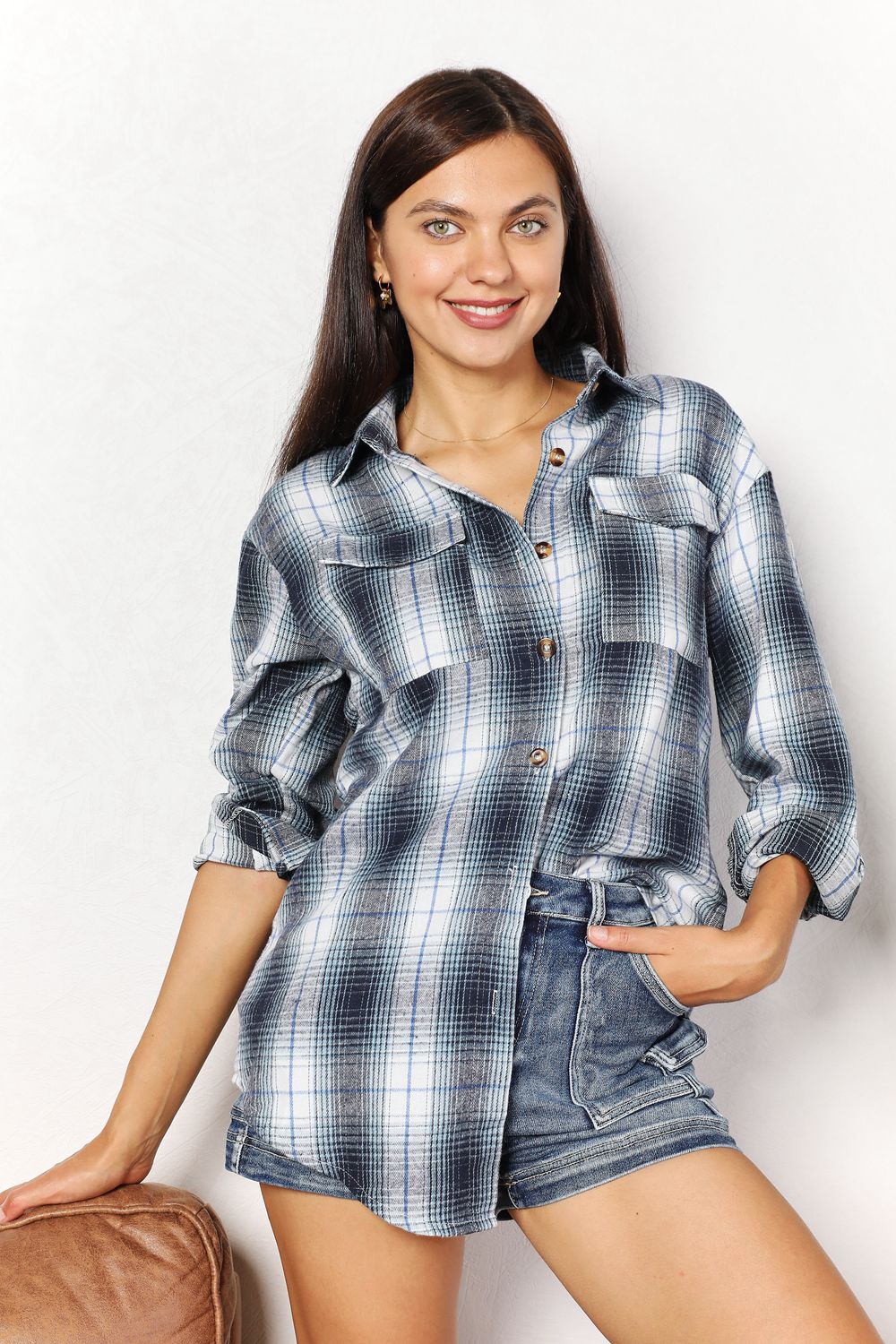 Woman wearing plaid dropped shoulder shirt styled with denim shorts, showcasing effortless elegance and versatile fashion.