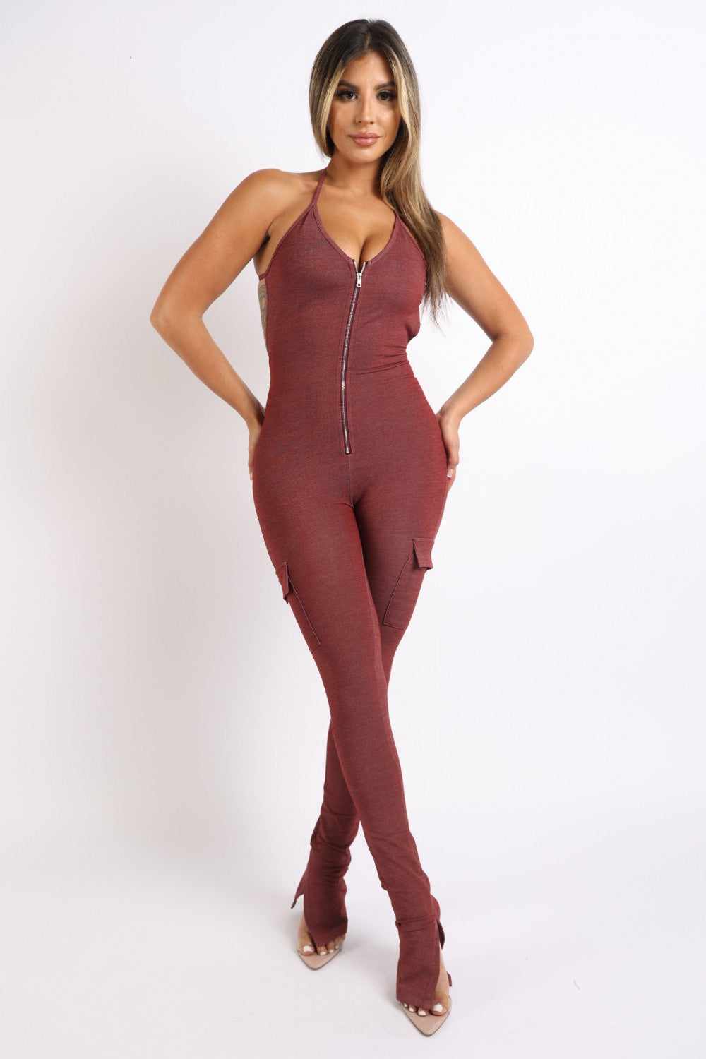 Woman wearing brick-colored cargo pocket halter jumpsuit made of rayon, polyester, and spandex.