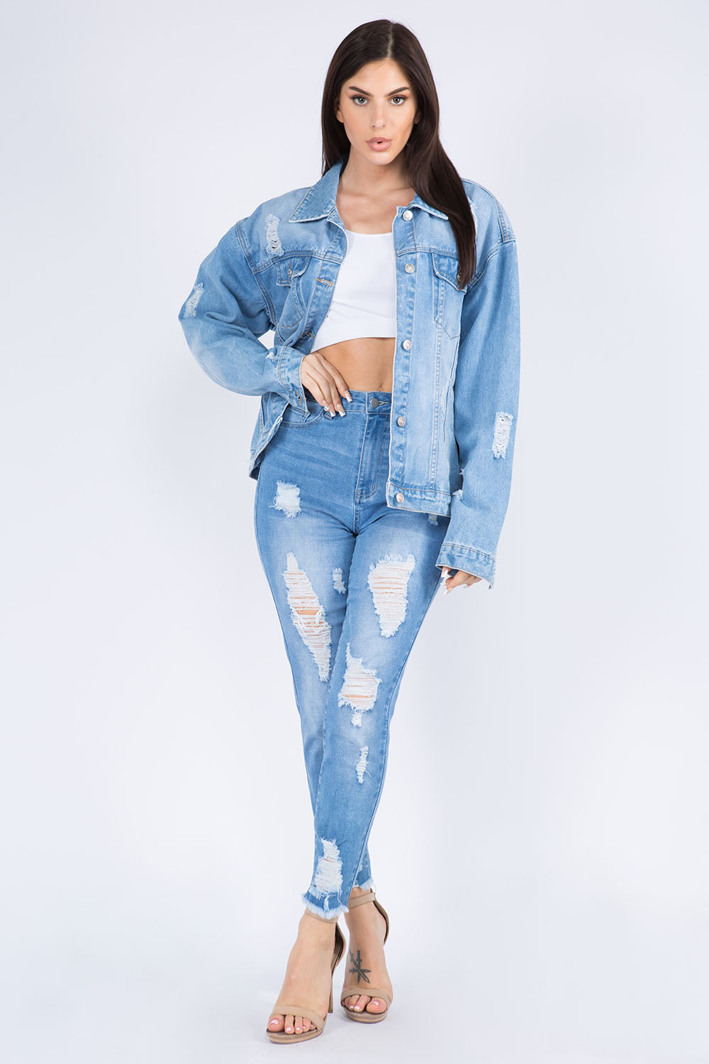 Woman wearing distressed denim jacket and jeans with a trendy painted back design, styled for a casual weekend look.