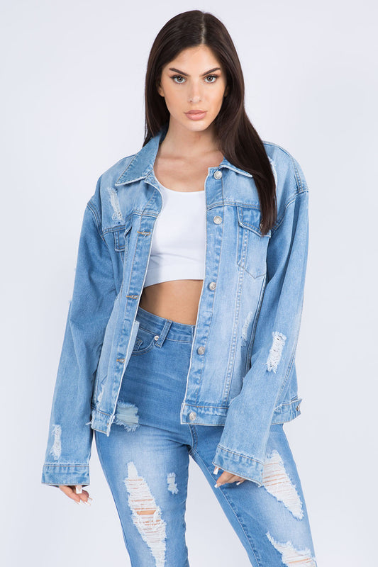 Woman wearing full-size distressed denim jacket with painted back design and relaxed fit, paired with ripped jeans for a trendy look.